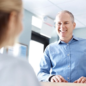 An older man speaking with a dental employee.