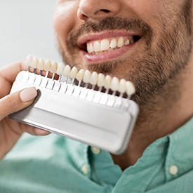 Dentist looking at shade scale next to patient's smile