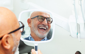 Man with black glasses smiling in reflection in mirror
