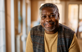 Closeup of man in plaid vest smiling at home