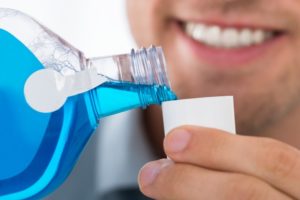 Smiling Petaluma dentist pouring antimicrobial mouthwash into cup during COVID-19