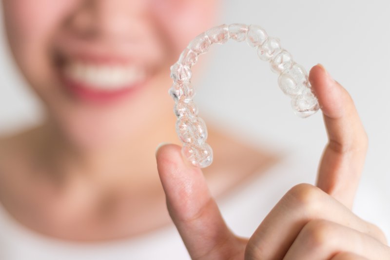 girl holding up Invisalign aligner