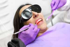 Woman in protective glasses undergoing laser dental service